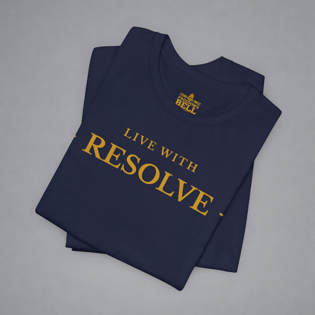 A folded navy blue t-shirt with gold text reading 'LIVE WITH RESOLVE' and a small 'BELLELL' logo printed inside the collar, displayed on a neutral gray background.