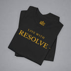A folded black t-shirt with gold text reading 'LIVE WITH RESOLVE' and a small 'BELL' logo printed inside the collar, displayed on a neutral gray background.