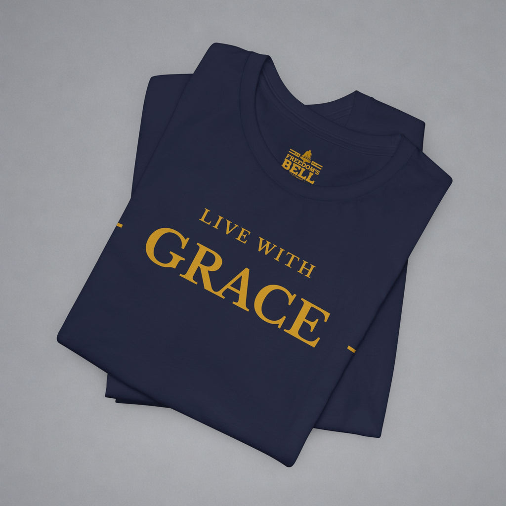 A folded navy blue t-shirt with gold text reading 'LIVE WITH GRACE' and a small 'BELLELL' brand logo printed inside the collar, displayed on a neutral gray background.