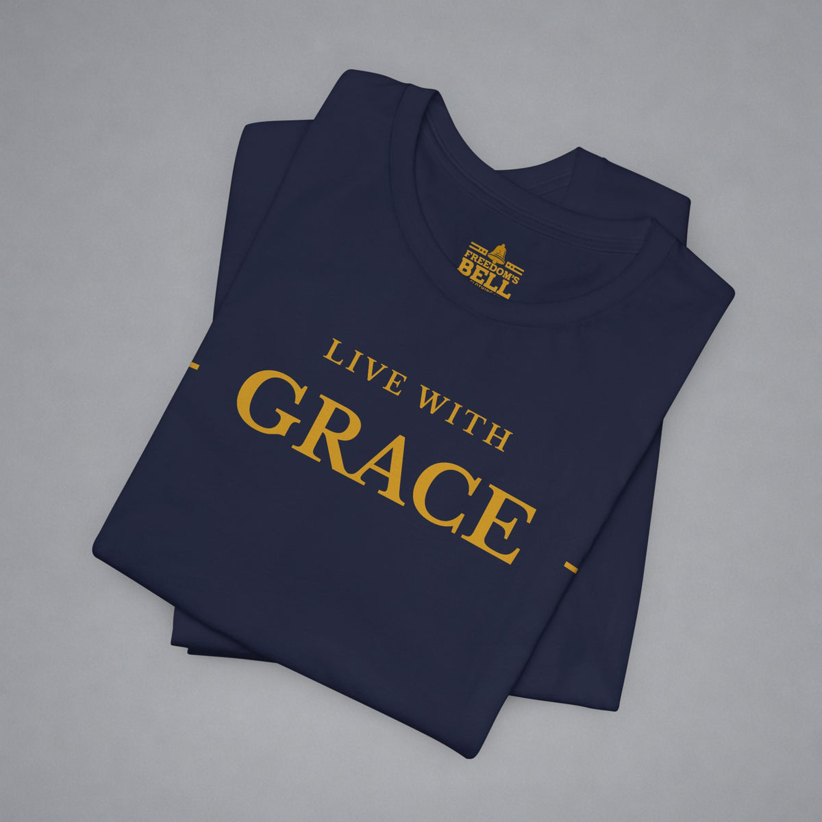A folded navy blue t-shirt with gold text reading 'LIVE WITH GRACE' and a small 'BELLELL' brand logo printed inside the collar, displayed on a neutral gray background.