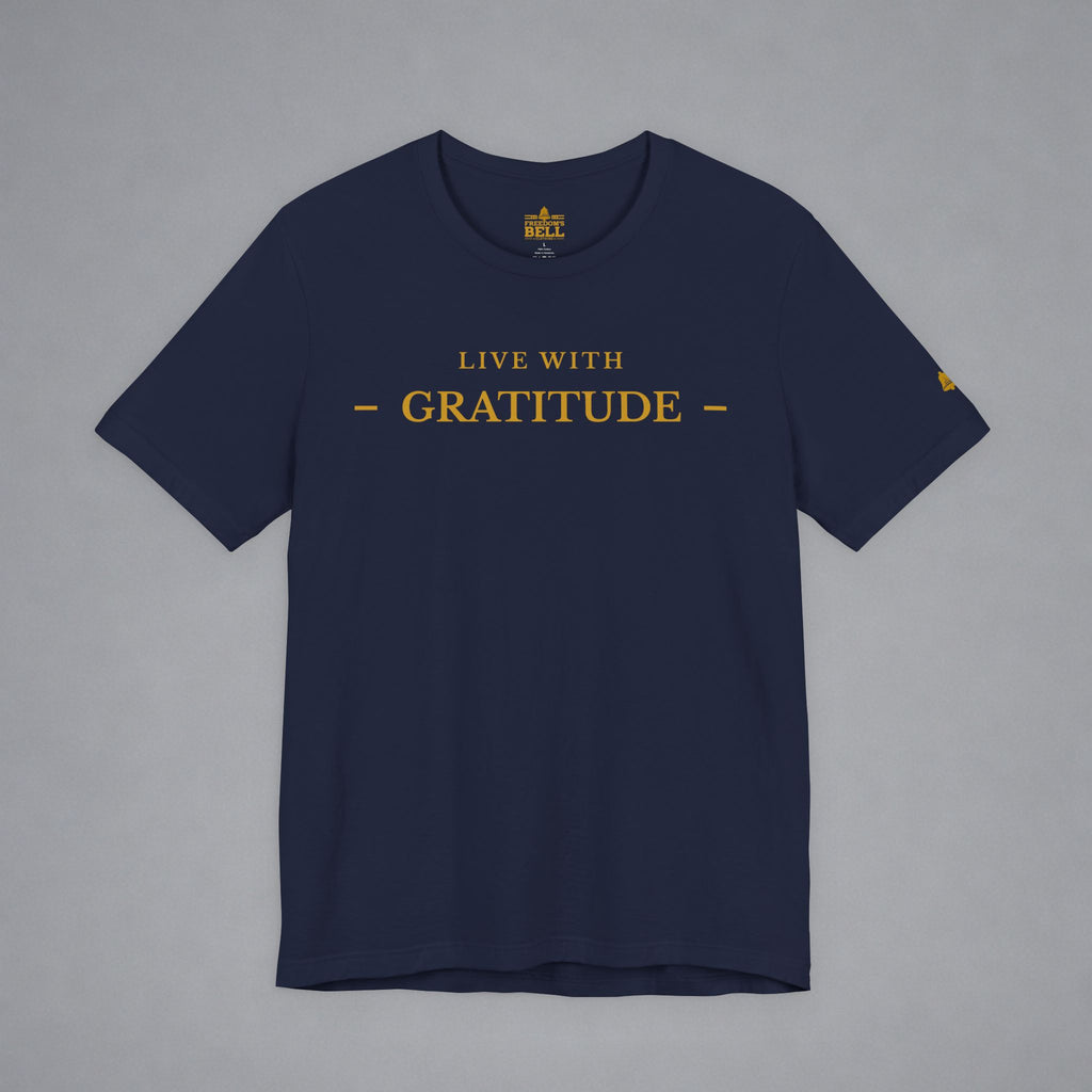 A navy blue short-sleeve t-shirt with 'LIVE WITH GRATITUDE' printed in gold across the chest, displayed flat against a neutral gray background.