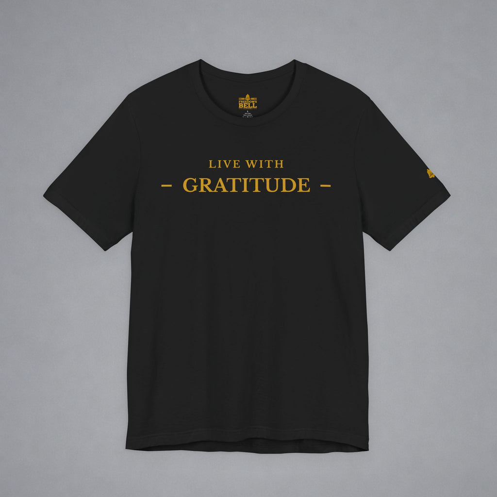 A black short-sleeve crewneck t-shirt with 'LIVE WITH GRATITUDE' printed in gold on the chest, displayed flat against a neutral gray background.