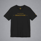A black short-sleeve crewneck t-shirt with 'LIVE WITH GRATITUDE' printed in gold on the chest, displayed flat against a neutral gray background.