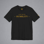 A black short-sleeve crewneck t-shirt with 'LIVE WITH - HUMILITY -' printed in gold across the chest, displayed flat against a neutral gray background.