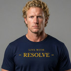 A man with curly blond hair wearing a navy blue crewneck t-shirt with the words 'LIVE WITH - RESOLVE -' printed in gold on the chest, set against a solid gray background.