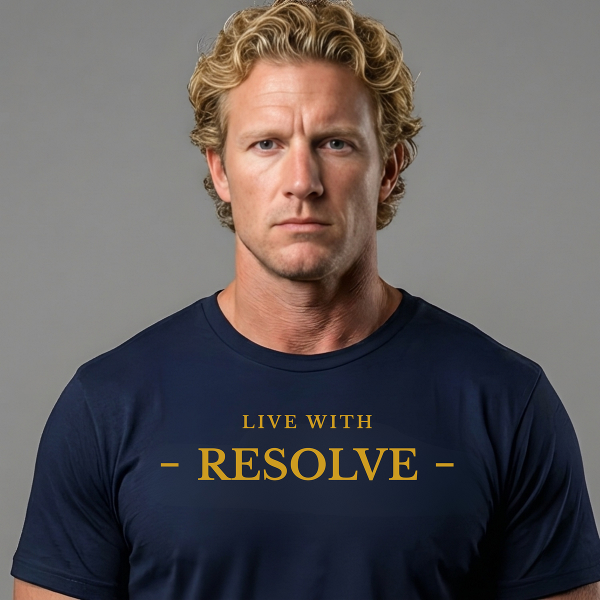 A man with curly blond hair wearing a navy blue crewneck t-shirt with the words 'LIVE WITH - RESOLVE -' printed in gold on the chest, set against a solid gray background.