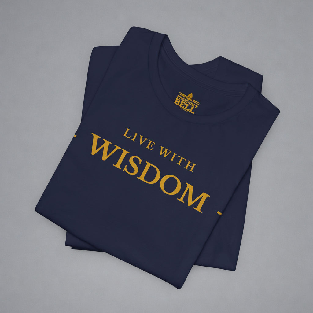 A folded navy blue t-shirt with gold text reading 'LIVE WITH WISDOM' and a small 'BELLS' logo printed inside the collar, displayed on a neutral gray background.