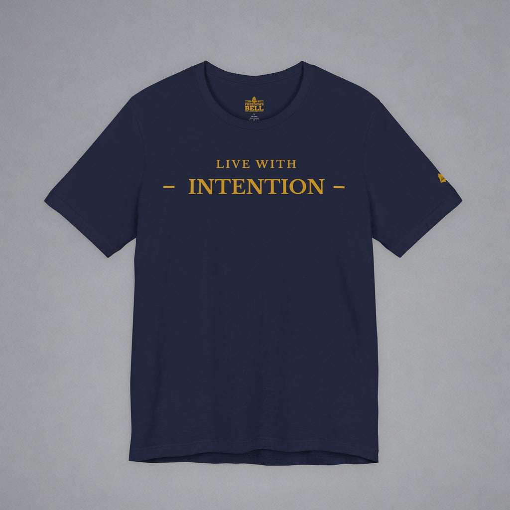 A navy blue short-sleeve t-shirt with 'LIVE WITH INTENTION' printed in gold across the chest, displayed flat against a neutral gray background.