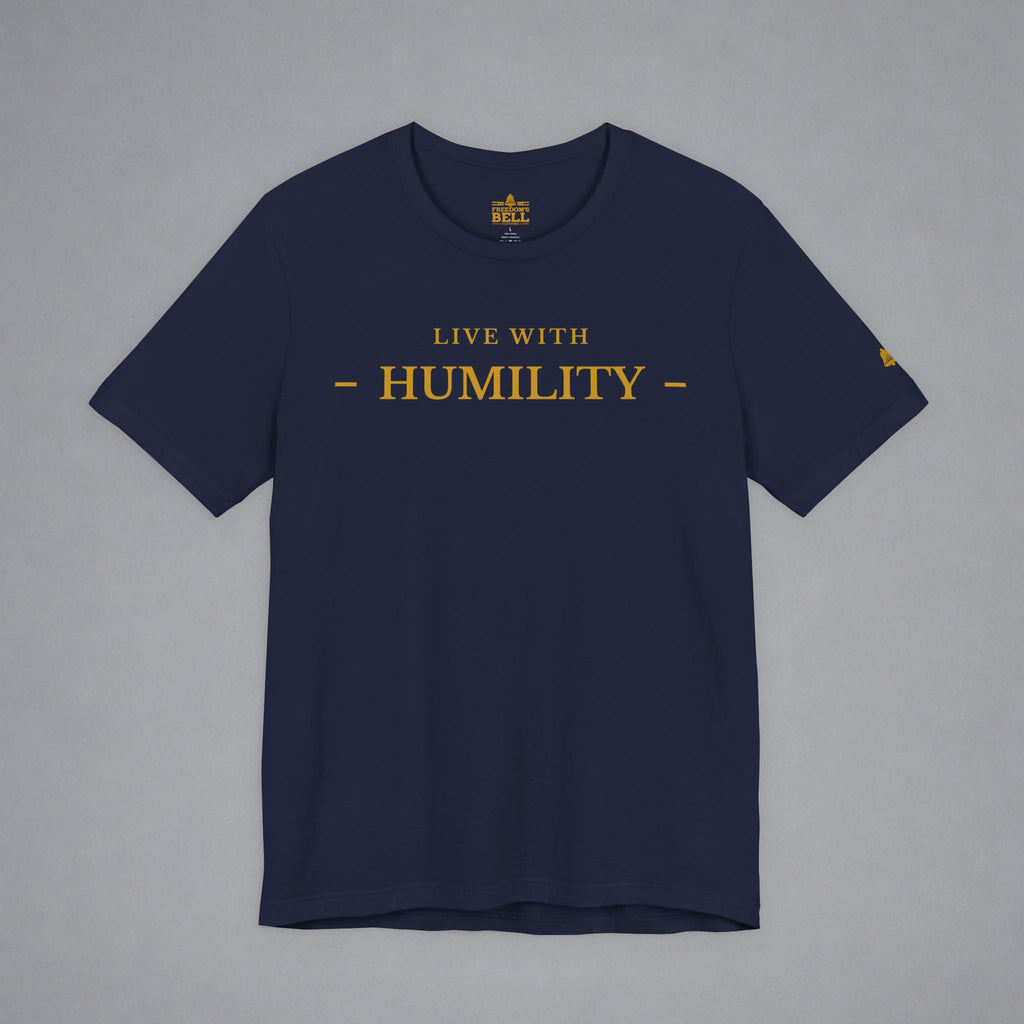 A navy blue crewneck t-shirt with 'LIVE WITH HUMILITY' printed in gold across the chest, displayed flat against a neutral gray background.