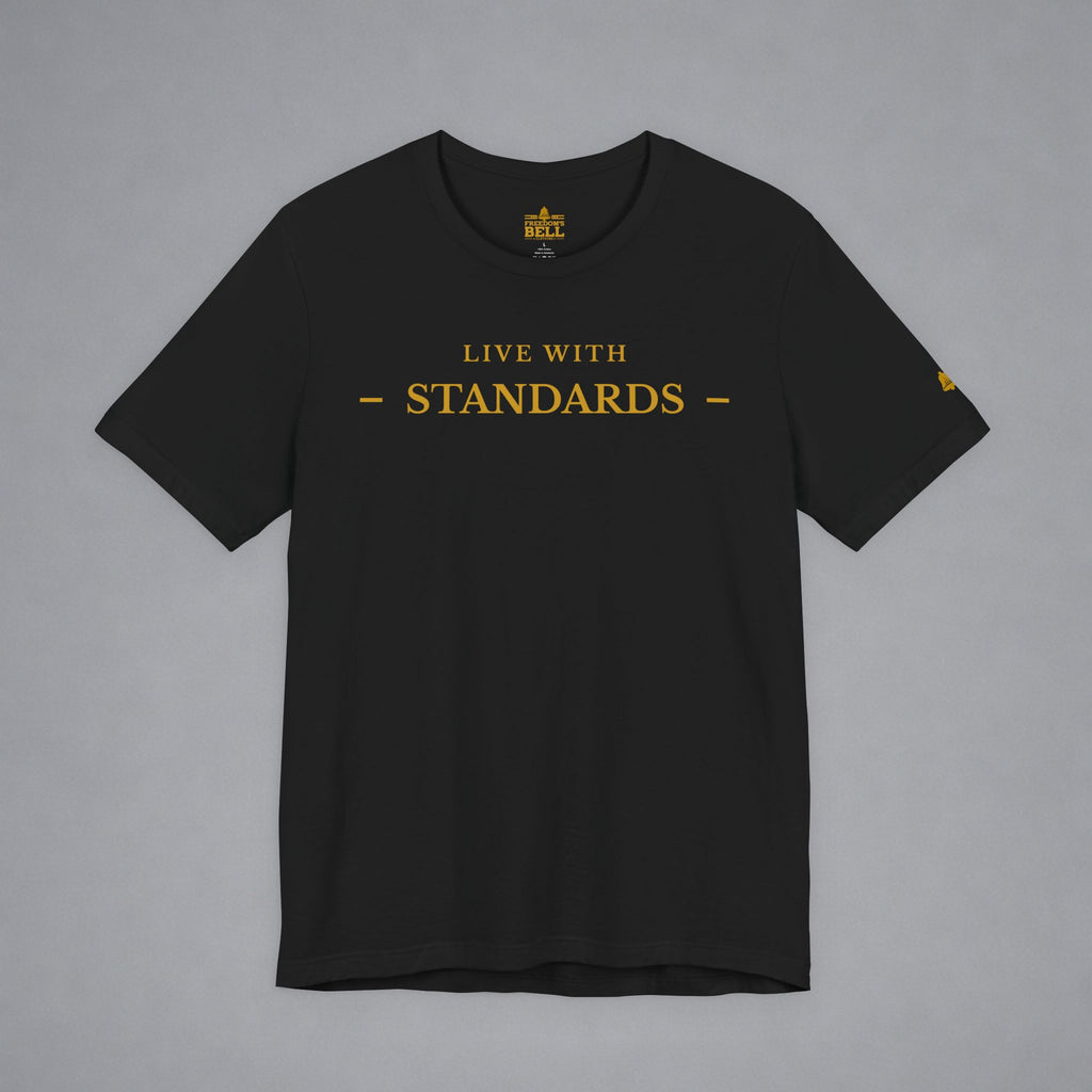 A black short-sleeve crewneck t-shirt with 'LIVE WITH STANDARDS' printed in gold across the chest, displayed flat against a neutral gray background.