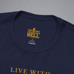 Close-up of a navy blue t-shirt showing the inner neck label with gold text that reads 'FREEDOM'S BELL A CLOTHING' and part of the gold 'LIVE WITH' text on the chest, set against a neutral gray background.